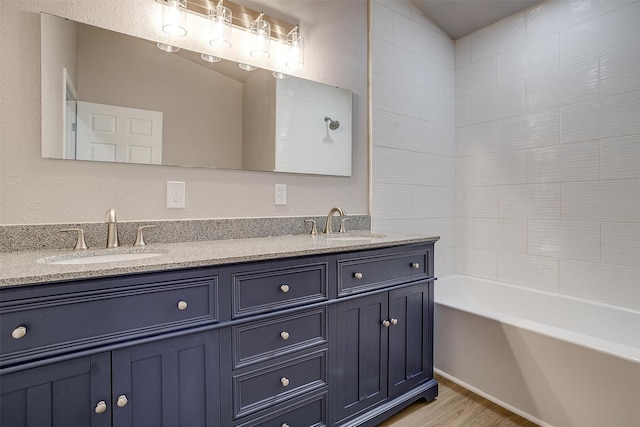 bathroom with vanity, lofted ceiling, hardwood / wood-style floors, and washtub / shower combination