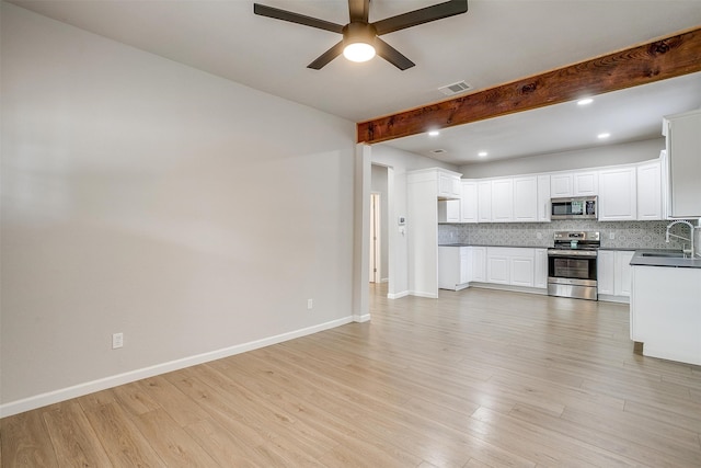 kitchen with sink, stainless steel appliances, beamed ceiling, decorative backsplash, and light hardwood / wood-style flooring