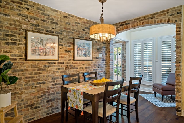 dining area featuring brick wall and dark hardwood / wood-style floors