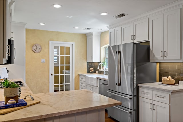 kitchen featuring white cabinets, tasteful backsplash, light stone countertops, and stainless steel fridge