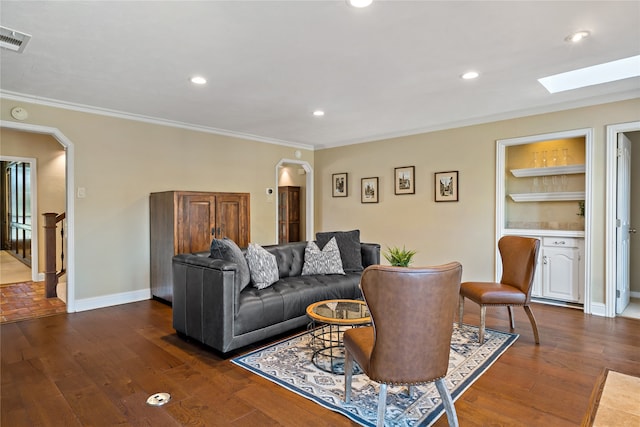 living room featuring a skylight, ornamental molding, built in features, and dark hardwood / wood-style flooring