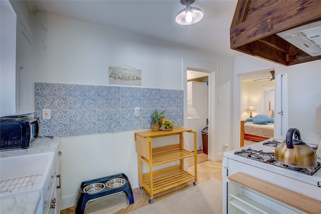 kitchen with ceiling fan, custom range hood, light parquet floors, and white range