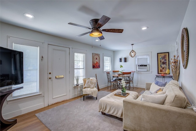 living room with ceiling fan, cooling unit, and light hardwood / wood-style flooring