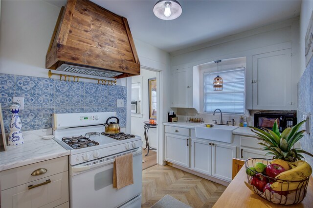 kitchen with premium range hood, sink, pendant lighting, white range with gas stovetop, and white cabinetry