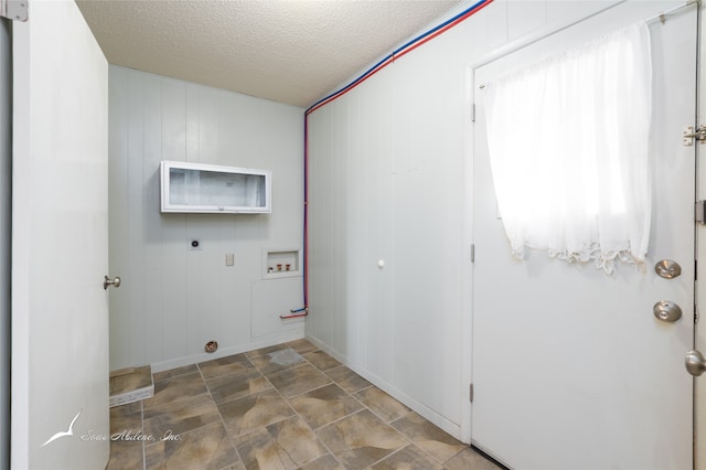 washroom featuring a textured ceiling, electric dryer hookup, washer hookup, and wooden walls