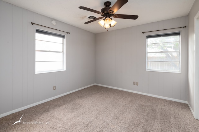 carpeted spare room with ceiling fan and plenty of natural light