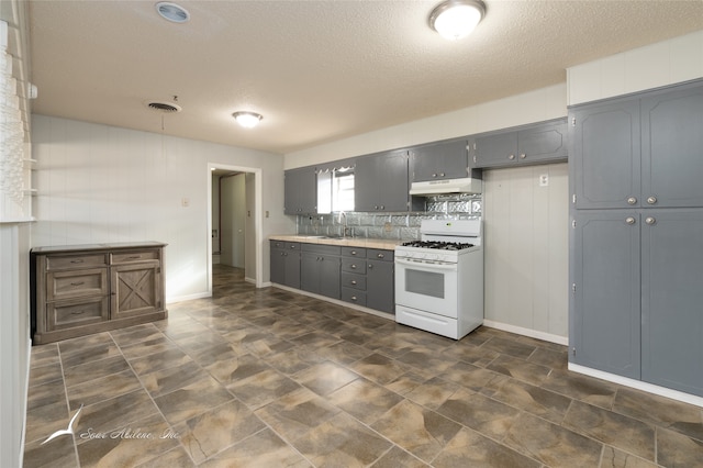 kitchen with tasteful backsplash, a textured ceiling, gray cabinetry, sink, and white gas range oven