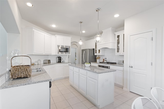 kitchen with white cabinetry, a center island, stainless steel appliances, pendant lighting, and custom range hood