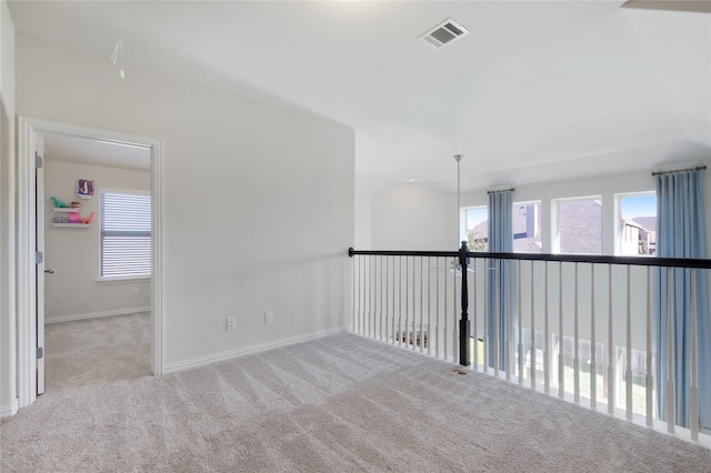 carpeted empty room featuring a wealth of natural light and vaulted ceiling