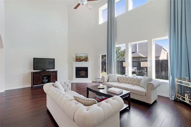 living room with a wealth of natural light, dark hardwood / wood-style floors, and a high ceiling