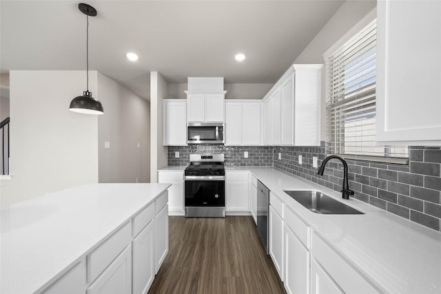 kitchen with sink, hanging light fixtures, appliances with stainless steel finishes, dark hardwood / wood-style flooring, and white cabinets