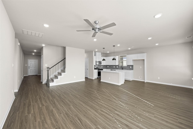 unfurnished living room with dark hardwood / wood-style flooring and ceiling fan