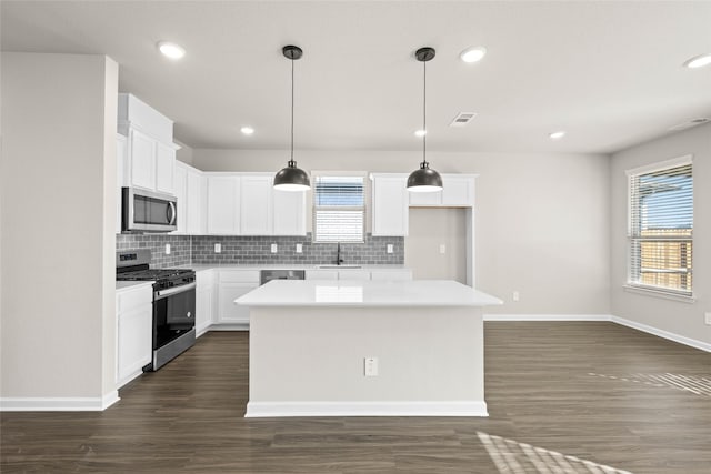 kitchen with appliances with stainless steel finishes, sink, white cabinets, backsplash, and a center island