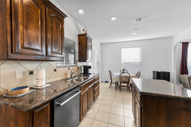 kitchen featuring sink, stainless steel dishwasher, a kitchen island, dark brown cabinets, and light tile patterned flooring