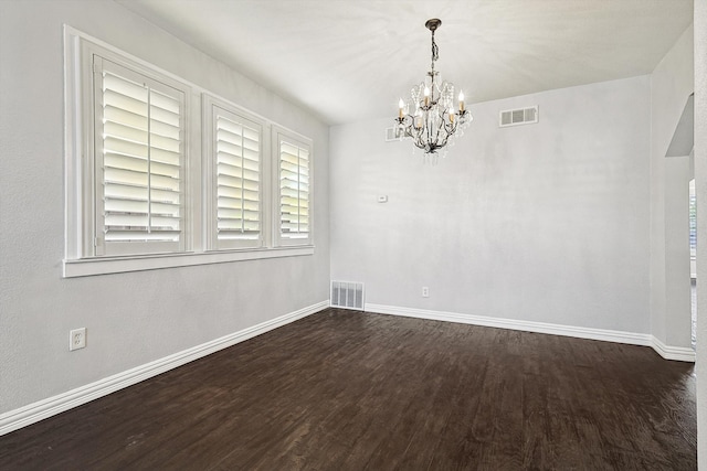 empty room with dark wood-type flooring and a notable chandelier