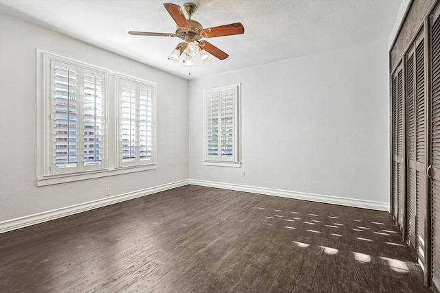 unfurnished bedroom with a closet, a textured ceiling, dark wood-type flooring, and ceiling fan