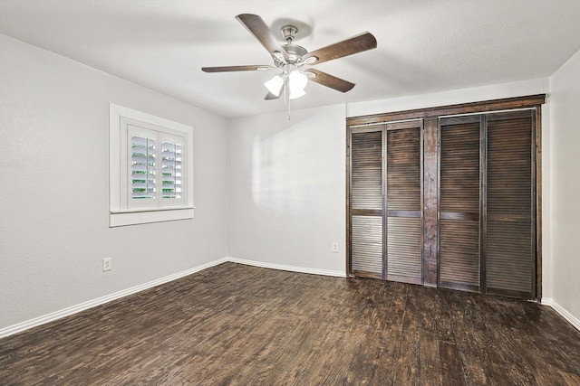 unfurnished bedroom featuring a closet, dark hardwood / wood-style floors, and ceiling fan