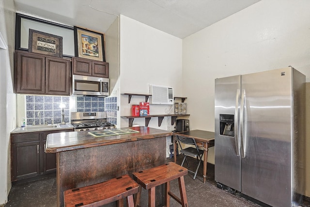 kitchen with tasteful backsplash, appliances with stainless steel finishes, dark brown cabinetry, and a wall mounted air conditioner