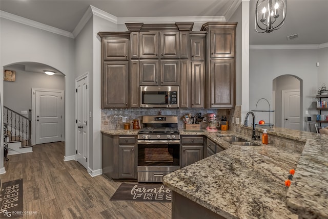 kitchen with dark brown cabinets, ornamental molding, dark hardwood / wood-style floors, sink, and stainless steel appliances