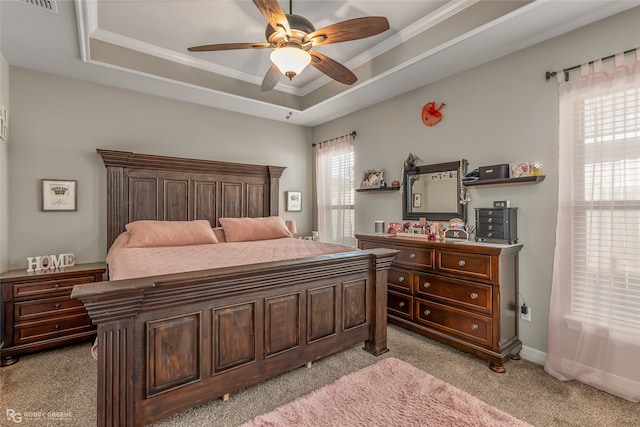 carpeted bedroom with crown molding, a tray ceiling, and ceiling fan