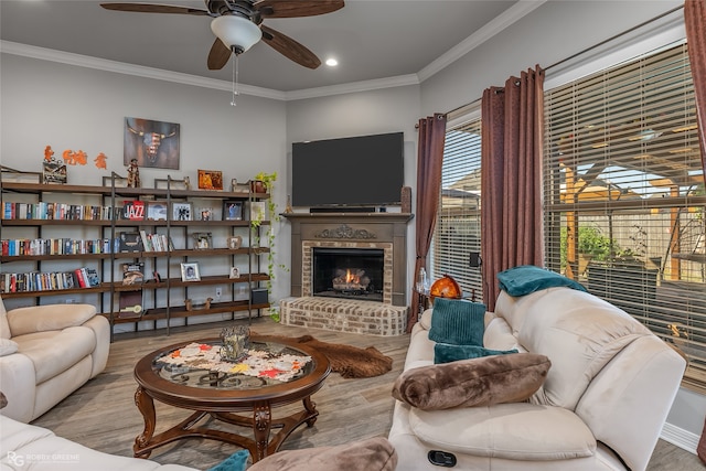 living room with light hardwood / wood-style floors, ornamental molding, ceiling fan, and a brick fireplace