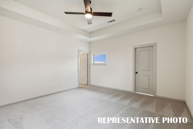 unfurnished room with ceiling fan, carpet, and a tray ceiling