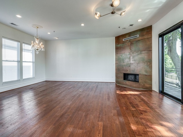 unfurnished living room with an inviting chandelier, dark hardwood / wood-style flooring, plenty of natural light, and a fireplace