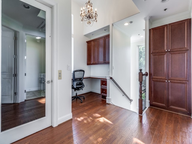 unfurnished office with built in desk, a notable chandelier, dark wood-type flooring, and ornamental molding