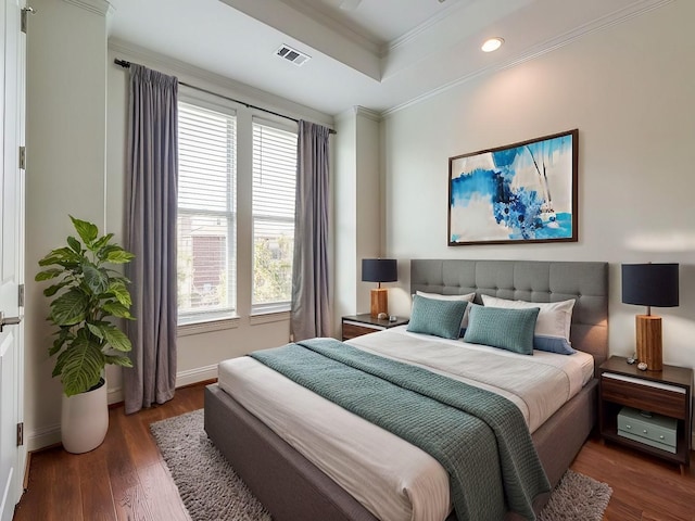 bedroom featuring ornamental molding, dark hardwood / wood-style flooring, and a tray ceiling