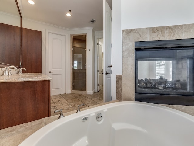 bathroom with vanity, crown molding, a multi sided fireplace, and a washtub