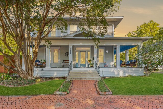 view of front of home featuring covered porch and a yard