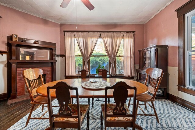 dining area featuring ceiling fan, a fireplace, a healthy amount of sunlight, and dark hardwood / wood-style floors