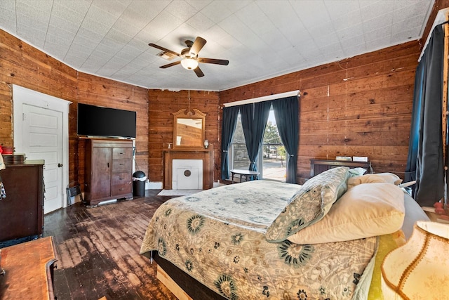 bedroom featuring dark wood-type flooring, ceiling fan, and wood walls