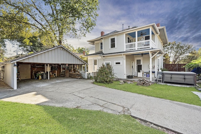 view of front of home featuring a hot tub, a balcony, ceiling fan, and a front lawn