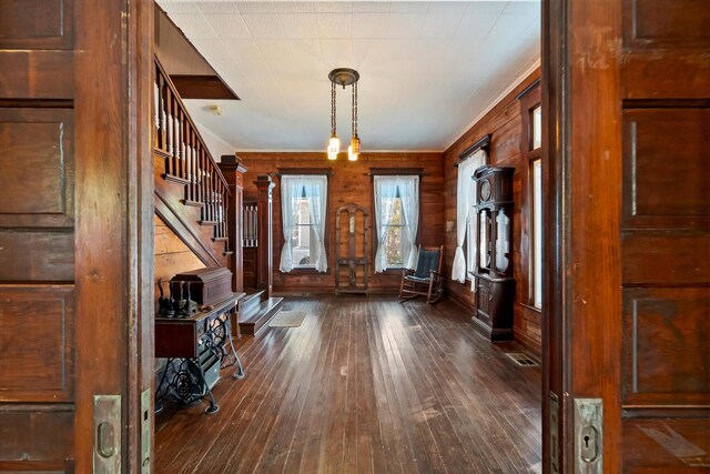 interior space featuring crown molding, ceiling fan with notable chandelier, hardwood / wood-style floors, and wood walls