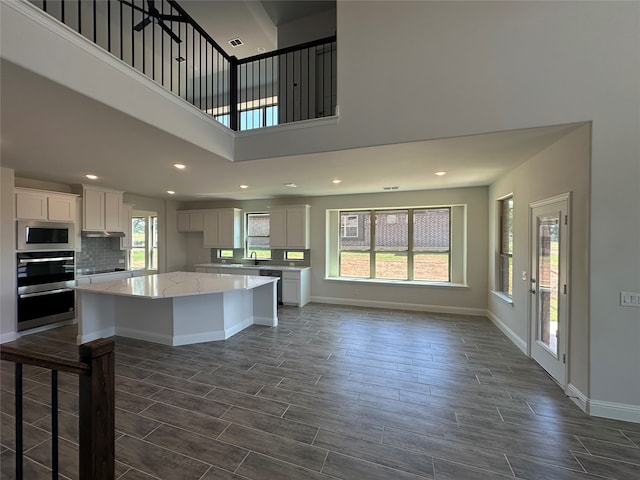 kitchen with a kitchen island, white cabinets, stainless steel microwave, and a healthy amount of sunlight