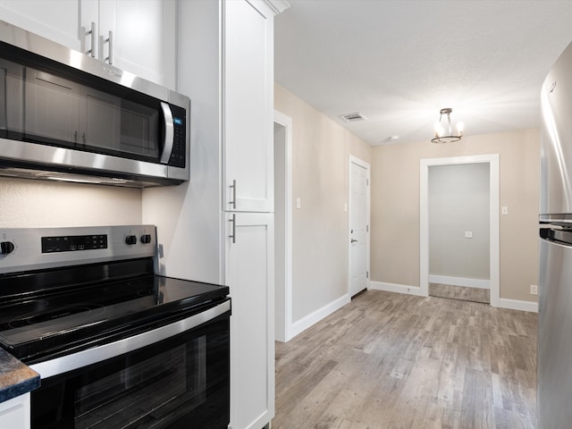 kitchen featuring white cabinetry, light hardwood / wood-style floors, stainless steel appliances, and a notable chandelier