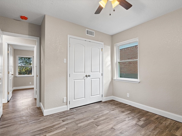 unfurnished bedroom with light hardwood / wood-style flooring, a textured ceiling, a closet, and ceiling fan