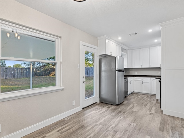 kitchen featuring white cabinets, a textured ceiling, light wood-type flooring, and stainless steel fridge