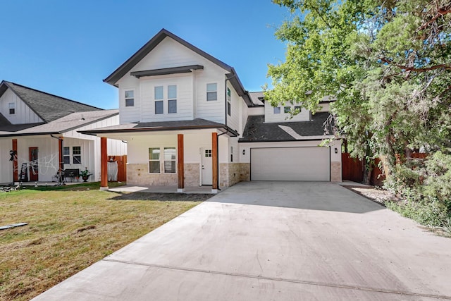 view of front of home featuring a front yard, covered porch, and a garage