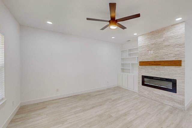 unfurnished living room featuring a stone fireplace, light hardwood / wood-style flooring, and ceiling fan