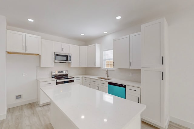 kitchen featuring appliances with stainless steel finishes, white cabinets, sink, and a kitchen island