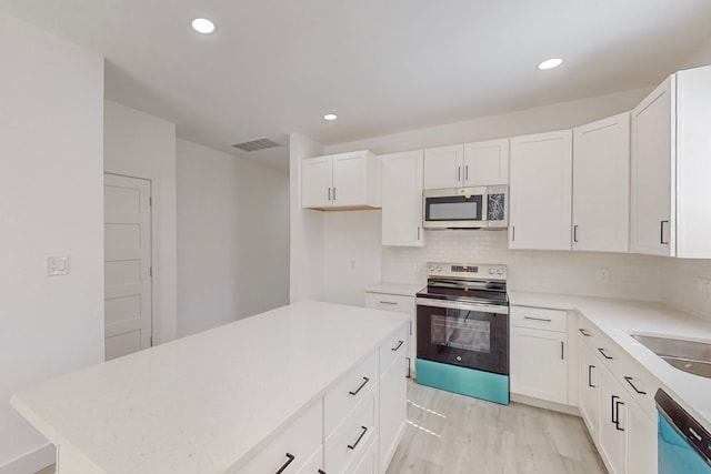 kitchen with white cabinetry, light hardwood / wood-style floors, appliances with stainless steel finishes, and a center island