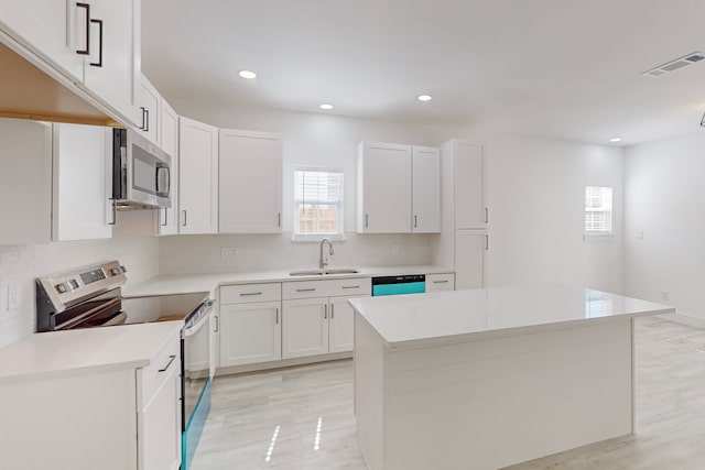 kitchen featuring appliances with stainless steel finishes, a center island, white cabinets, and sink