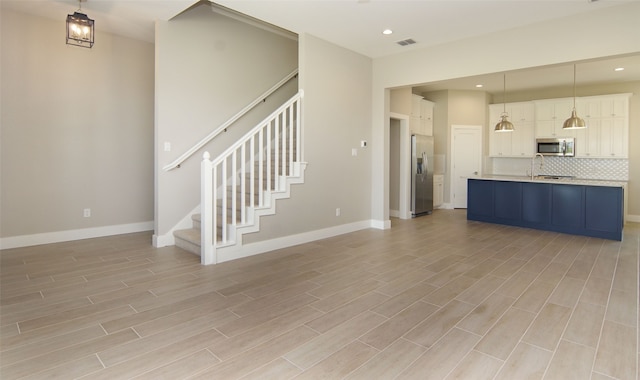 unfurnished living room with sink and light wood-type flooring