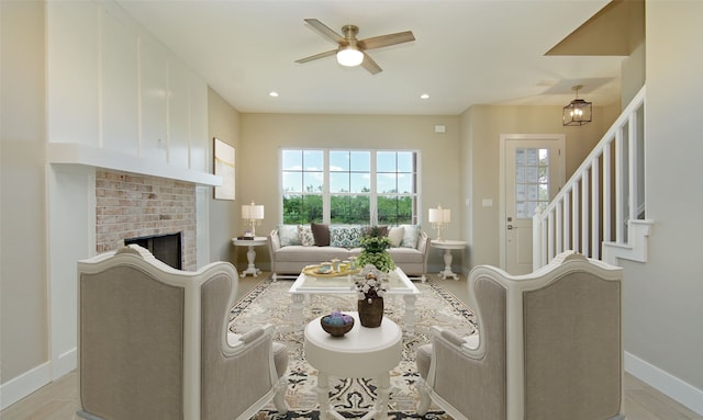 living room featuring light hardwood / wood-style floors, a brick fireplace, and ceiling fan