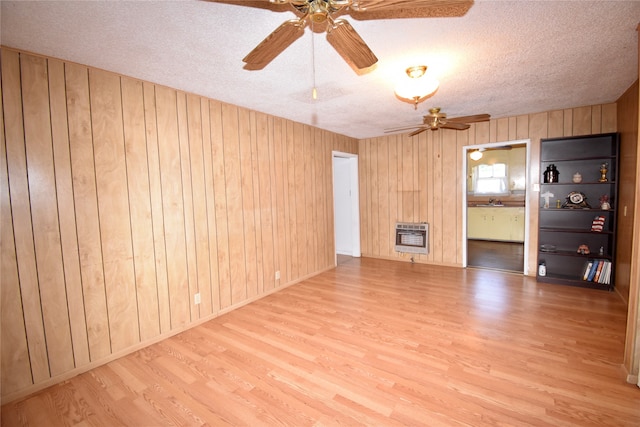 empty room featuring a textured ceiling, hardwood / wood-style flooring, heating unit, and wooden walls