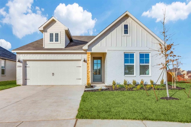 view of front of property with board and batten siding, a front yard, brick siding, and an attached garage