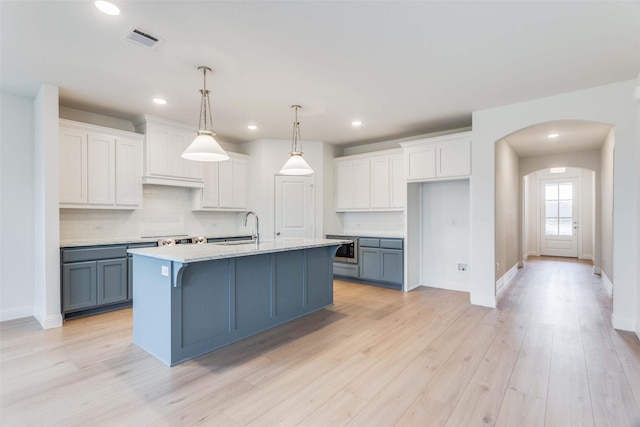 kitchen with a sink, visible vents, white cabinetry, light countertops, and hanging light fixtures