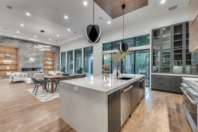 kitchen featuring high end range, light wood-type flooring, a spacious island, sink, and pendant lighting